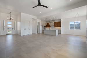 Unfurnished living room featuring a chandelier, ceiling fan, baseboards, recessed lighting, and a sink