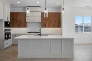 Kitchen featuring stainless steel oven, a sink, built in microwave, light countertops, and decorative backsplash