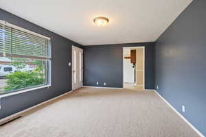 Carpeted empty room featuring baseboards and a textured ceiling
