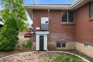 View of exterior entry with fence, brick siding, and crawl space