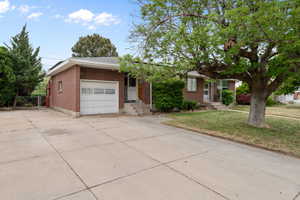 Ranch-style home featuring a garage, brick siding, driveway, and a front lawn