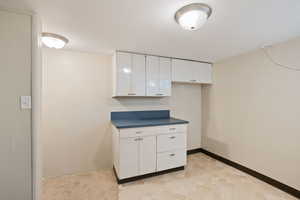 Kitchen featuring white cabinets, dark countertops, and baseboards