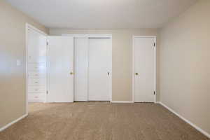 Unfurnished bedroom featuring carpet, baseboards, a closet, and a textured ceiling