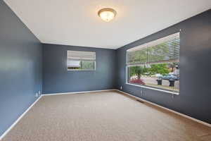Carpeted empty room featuring baseboards and a textured ceiling