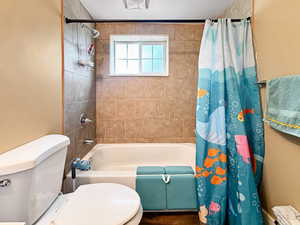 Full bath featuring shower / bathtub combination with curtain and toilet