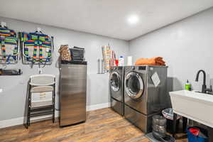 Clothes washing area featuring washing machine and dryer, wood finished floors, and baseboards