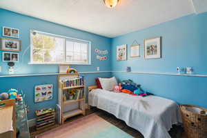 Bedroom with wood finished floors, baseboards, and a textured ceiling