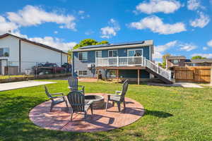 Back of property featuring stairs, a fire pit, solar panels, a deck, and a patio area