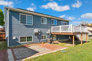 Back of property with a wooden deck, stairway, a lawn, a patio area, and central AC