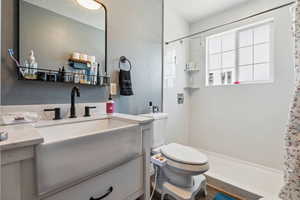 Bathroom with curtained shower, toilet, and vanity