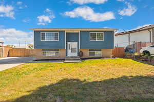 Raised ranch featuring brick siding, entry steps, and concrete driveway