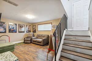 Living room featuring stairway, baseboards, and wood finished floors