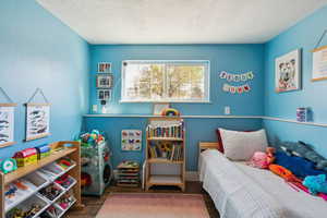 Bedroom with a textured ceiling and wood finished floors