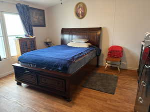 Bedroom featuring light wood-style floors, multiple windows, and baseboards
