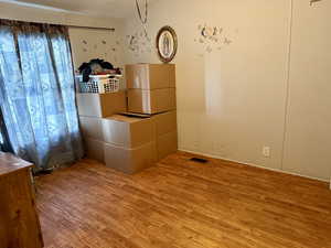 Unfurnished bedroom with wood finished floors, a textured ceiling, and freestanding refrigerator