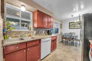 Kitchen with dishwasher, freestanding refrigerator, a sink, light tile patterned floors, and light countertops