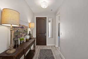 Doorway with light wood finished floors and baseboards