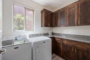 Laundry room featuring washer and clothes dryer, cabinet space, and light wood-type flooring
