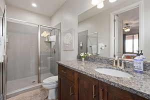 Full bathroom with a shower stall, toilet, ceiling fan, and vanity