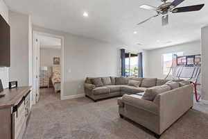 Living room featuring light carpet, ceiling fan, baseboards, and recessed lighting