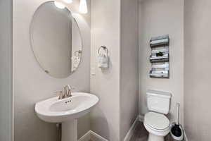 Bathroom featuring toilet, baseboards, and wood finished floors