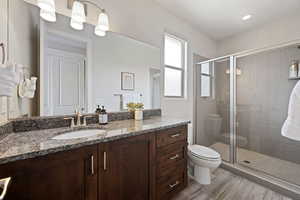 Bathroom featuring toilet, a shower stall, vanity, and wood finished floors