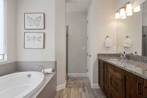 Full bath featuring vanity, a garden tub, wood finished floors, and a stall shower