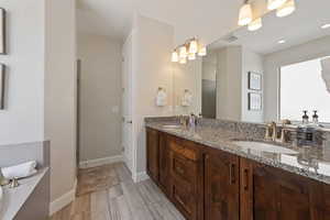Full bath featuring double vanity, baseboards, and wood finished floors
