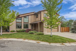 View of front facade featuring concrete driveway, an attached garage, central air condition unit, and brick siding