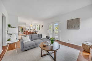Living room with light wood finished floors, baseboards, french doors, and a chandelier