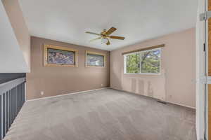 Carpeted spare room with ceiling fan and baseboards