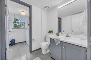 Bathroom with separate washer and dryer, toilet, vanity, and baseboards