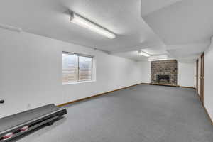 Below grade area with a large fireplace, baseboards, a textured ceiling, and carpet flooring