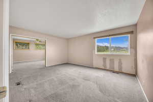 Carpeted spare room featuring baseboards, a ceiling fan, and a textured ceiling