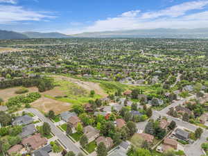 Aerial view of property and surrounding area featuring a mountainous background and nearby suburban area