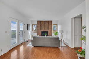 Living room featuring light wood-style flooring, baseboards, and a brick fireplace