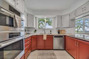 Kitchen featuring appliances with stainless steel finishes, a sink, backsplash, and light stone countertops