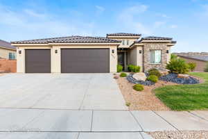 View of front of house featuring stucco siding, a garage, driveway, a tile roof, and stone siding