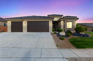 Prairie-style house featuring an attached garage, stucco siding, concrete driveway, a tiled roof, and stone siding
