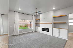 Unfurnished living room with a ceiling fan, baseboards, a large fireplace, light wood-style floors, and recessed lighting