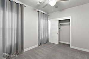 Unfurnished bedroom with carpet, baseboards, a closet, and ceiling fan
