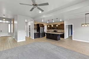 Kitchen with stainless steel appliances, open floor plan, dark brown cabinetry, and recessed lighting