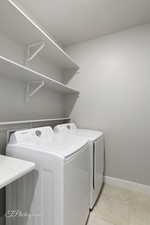 Washroom with washer and dryer, baseboards, and light tile patterned floors