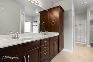 Full bathroom with tile patterned floors, a shower stall, double vanity, and baseboards