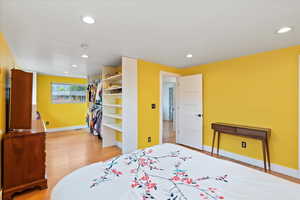 Bedroom featuring light wood-type flooring, baseboards, recessed lighting, large walk-in closet