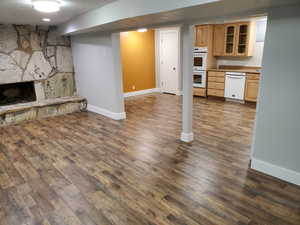 Unfurnished living room featuring baseboards, a stone fireplace, and dark wood-type flooring
