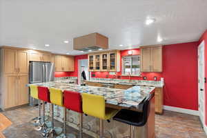 Kitchen featuring a sink, appliances with stainless steel finishes, a kitchen island, baseboards