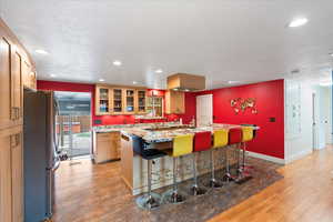Kitchen with freestanding refrigerator, recessed lighting, baseboards, large island, and glass insert cabinets