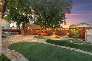 View of yard featuring a hot tub, a patio area, a fire pit, an outdoor structure, and a storage unit