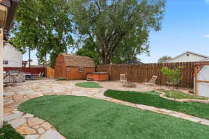 View of yard with a hot tub, a fire pit, a patio area, a shed, and an outbuilding